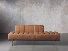 a tan couch sitting on top of a metal frame in front of a concrete wall