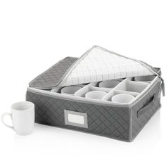 an open storage box with cups in it next to a coffee cup and saucer