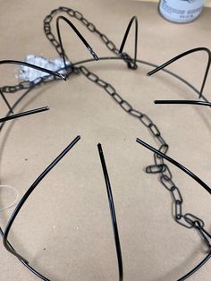 a cat's head made out of metal wire and chains on a table next to a can of paint