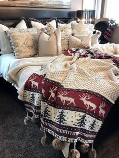 a bed covered in lots of pillows and blankets on top of a carpeted floor