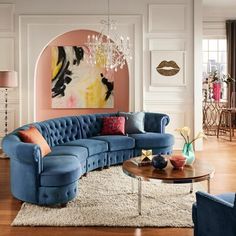 a living room filled with green couches and a chandelier hanging from the ceiling