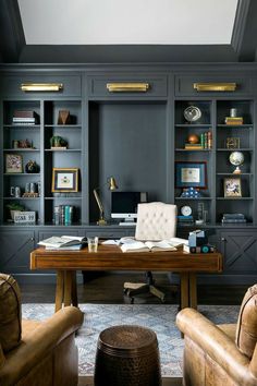 an office with built - in bookcases, leather chairs and a wooden desk