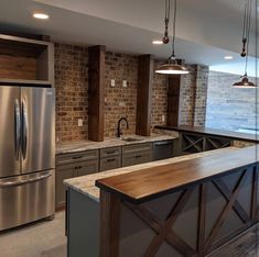 a large kitchen with an island in the middle and brick walls on both sides, along with stainless steel appliances