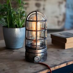 a lamp that is sitting on a table next to a potted plant and books