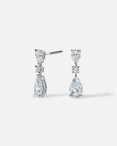 two pear shaped diamond earrings on a white background