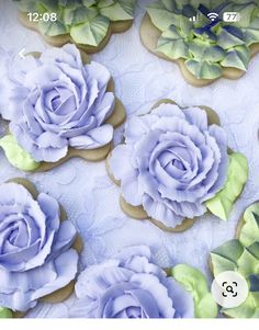 cookies decorated with blue and green flowers on a white tablecloth for a wedding or special occasion