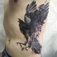 a black and grey bird tattoo on the side of a man's stomach