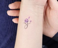 a woman's wrist tattoo with a single purple flower on the left side of her arm