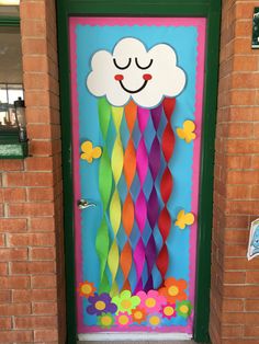 a colorful door decorated with paper flowers and a smiling cloud on the top of it