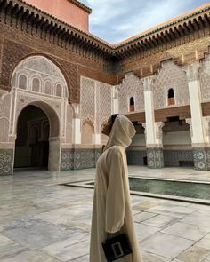 a person standing in front of a building with tiled walls and arches on either side