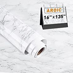 a roll of white paper next to a calendar on a marble counter top with an adhesiver