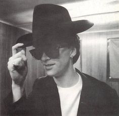 black and white photograph of a man wearing a cowboy hat, sunglasses and jacket in an elevator