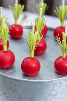 red radishes with green stems are arranged on a silver platter