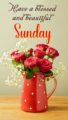 a red vase filled with roses and baby's breath on top of a wooden table