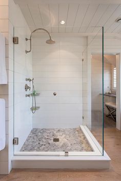 a walk in shower sitting next to a white wall and wooden floored bathroom area