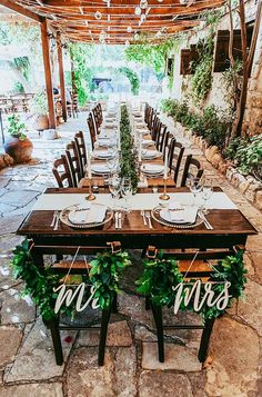 a table set up for a wedding with mr and mrs signs hanging from the ceiling