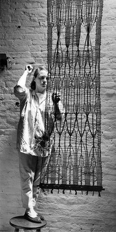 a man standing on top of a skateboard next to a wire structure that is attached to a brick wall