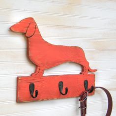 a red dog coat rack hanging on the side of a white wall with hooks attached to it