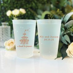 two frosted cups sitting next to each other on a table with flowers in the background