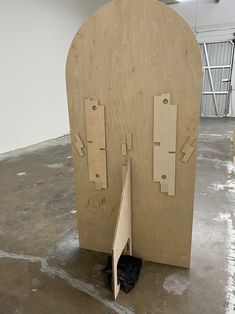 a large wooden sculpture with two doors open on the floor in an empty room that appears to be unfinished