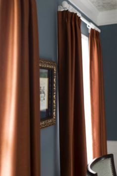 the curtains are hanging in front of the window with an ornate gold frame on it