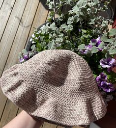 a crocheted hat sitting on top of a wooden table next to a potted plant