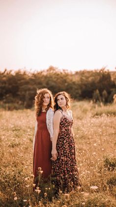 two women standing in a field with tall grass