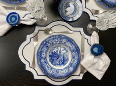 a blue and white dinner set on a table with silverware, napkins and glasses