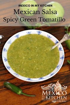 mexican spicy green tomato sauce in a white and blue bowl on a wooden table with a spoon