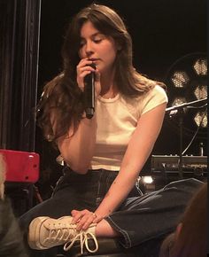 a woman sitting on top of a stool holding a microphone