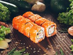 sushi rolls on a wooden table surrounded by vegetables