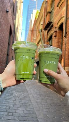 two people holding green drinks in their hands