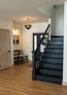 a staircase leading to the second floor in a home with hardwood floors and white walls