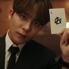 a man in a suit holding up a card with the anarchy symbol on it's side