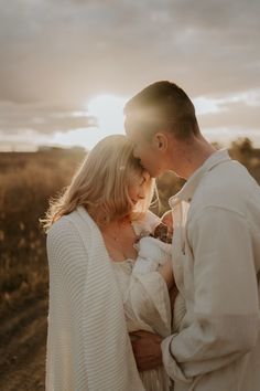 a man and woman holding a baby in their arms while standing on a dirt road