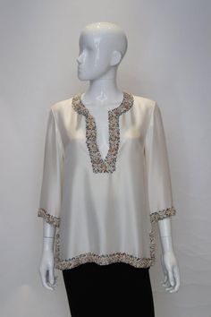 About A stunning ivory kafta top with bead and shell decoration. The kaftan is lined in silk and has 4'' slits on either side. It has a round neckline with a central opening with hook and eye fastening. It is quite heavy . Details PLACE OF ORIGIN Unknown PERIOD 1970-1979 MATERIAL NOTES Silk CONDITION Good BUST 38 in. (96.52 cm) SHOULDER TO HEM 27 in. (68.58 cm) Silk Overlay, Lurex Dress, Kaftan Top, Orange Skirt, Silk Kaftan, Poncho Tops, Womens Blouses, Hook And Eye, Vintage Jeans