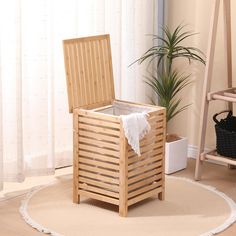 a wooden laundry hamper sitting on top of a rug next to a potted plant