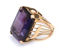 - Stunning Large Amethyst and 12k Yellow Gold Ring- Ring band forms a platform for stone with graphic geometric detail on sides - Unique band with flat back- Rectangular Amethyst stone measures 22mm tall by 16mm wide and 6.5mm deep - Ring face measures .9" tall by .63" wide and .46" deep- Stone has two flea bites out of it: one on top and one on the corner, otherwise excellent condition- Ring weighs 11.5 grams- Ring has four distinct hallmarks stamped on the band, they appear European Luxury Elegant Amethyst Ring With Large Stone, Luxury Amethyst Rectangular Stone Ring For Gift, Rectangular Amethyst Ring In Yellow Gold, Rectangular Amethyst Rings In Yellow Gold, Rectangular Amethyst Ring In 14k Gold, Yellow Gold Amethyst Ring With Rectangular Shape, Gold Rectangular Amethyst Ring, Yellow Gold Amethyst Ring, Month Gemstones