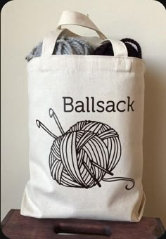 a ball of yarn sitting on top of a wooden stand next to a white bag