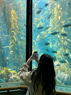 a woman taking a photo of fish in an aquarium