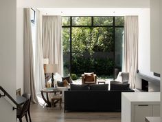 a living room filled with furniture next to a large window covered in white drapes