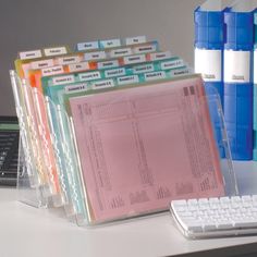 there are many binders on the desk next to a keyboard and computer mouses