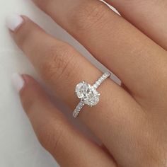 a woman's hand with a diamond ring on top of her finger and an engagement band