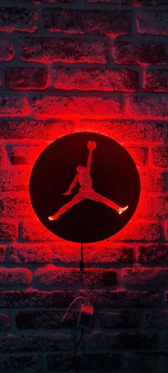 a red neon sign hanging from the side of a brick wall with an air jordan logo on it