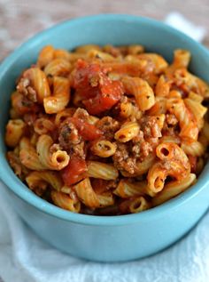 a blue bowl filled with pasta covered in meat and tomato sauce on top of a white towel