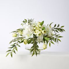 a vase filled with white flowers and greenery