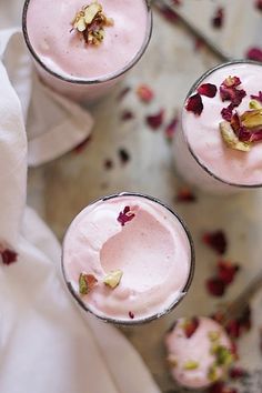 three glasses filled with ice cream sitting on top of a white cloth covered in flowers