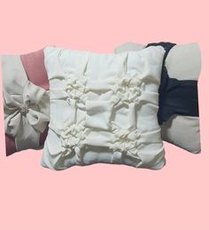 three pillows with bows on them against a pink background