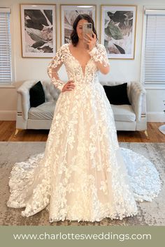 a woman in a wedding dress taking a selfie with her cell phone while standing in front of a couch