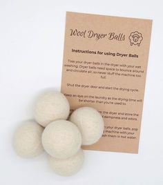 four balls of wool dryer balls sitting on top of a piece of paper next to an instruction card